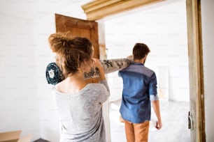 Young married couple moving in new house, carrying a carpet together.