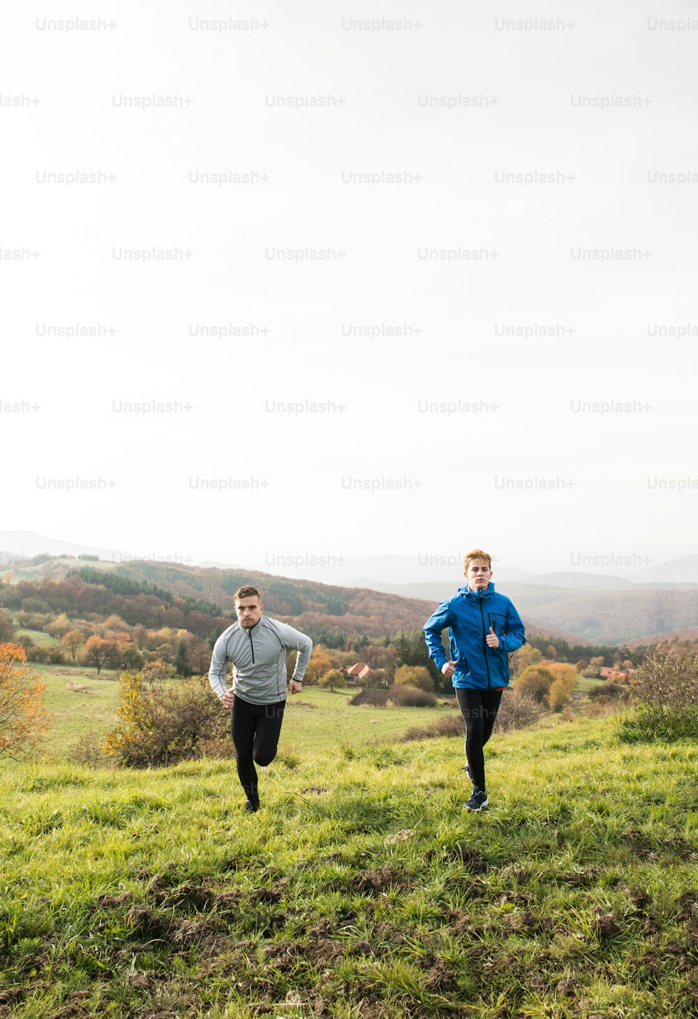 Two young handsome hipster athletes in sports jackets running in sunny autumn nature