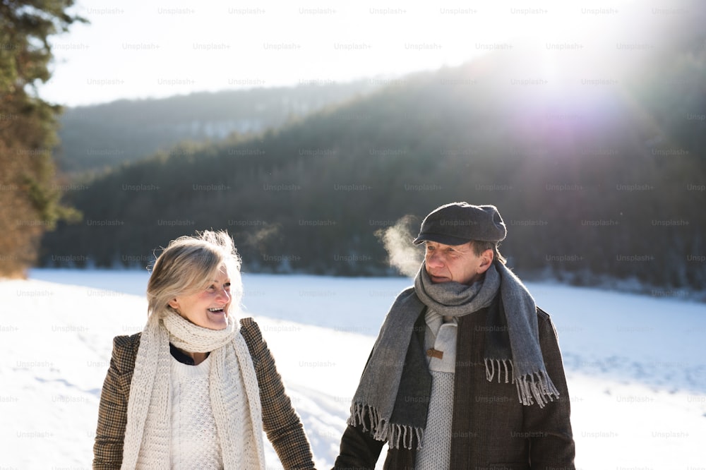 Beautiful senior woman and man on a walk in sunny winter nature.