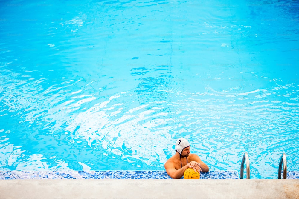 Joueur de water-polo dans une piscine. L’homme fait du sport.
