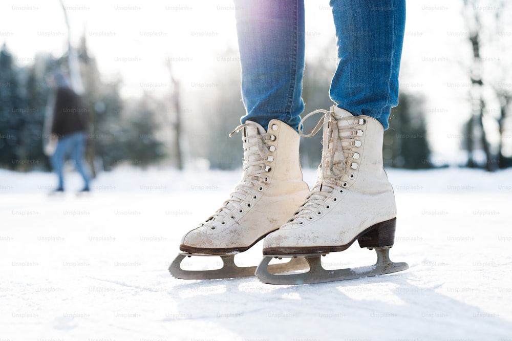 Gambe di donna irriconoscibile in un soleggiato pattinaggio sul ghiaccio della natura invernale, primo piano.