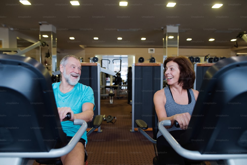 Schönes fittes älteres Paar in Sportkleidung im Fitnessstudio, das Cardio-Training macht und auf einem Liegerad trainiert. Sport Fitness und gesunder Lebensstil Konzept.