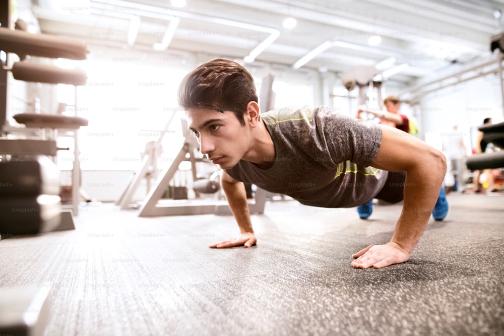 Fit hispanic man in gym training, doing push ups