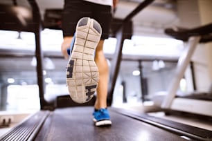 Unrecognizable fitness man in gym doing cardio workout, exercising on treadmill. Close up of sole of his shoe. Sport fitness and healthy lifestyle concept.