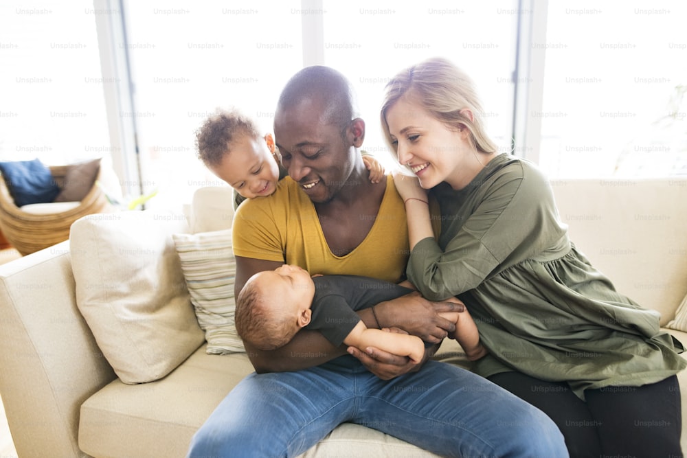 Beautiful young interracial family at home with their cute daughter and little baby son.