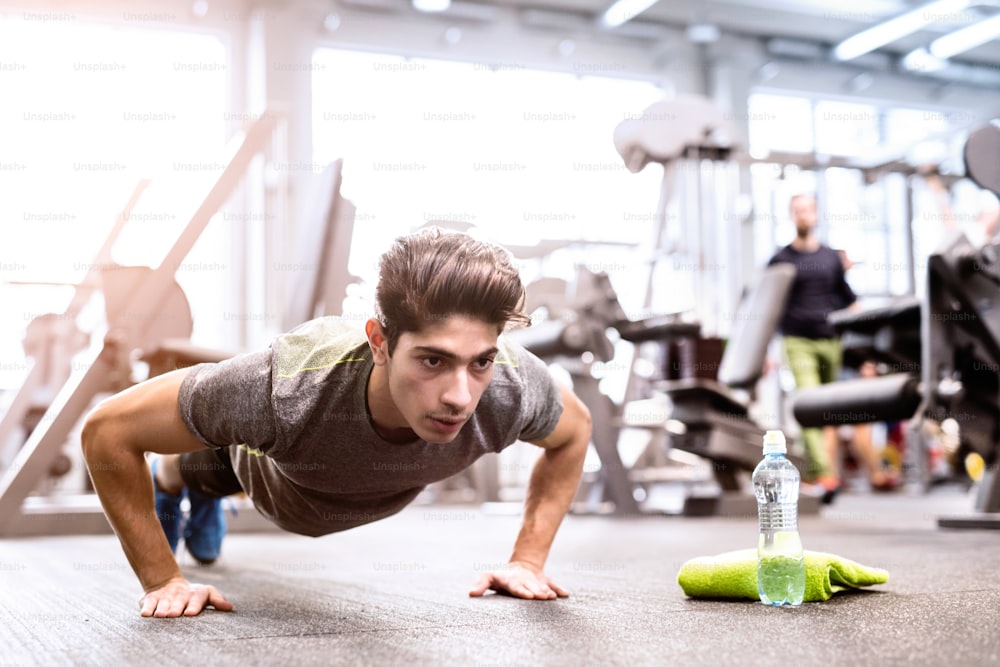 Fit hispanic man in gym training, doing push ups