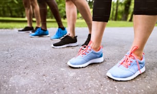 Primer plano de las piernas de los jóvenes atletas preparados para correr en el parque verde soleado del verano.