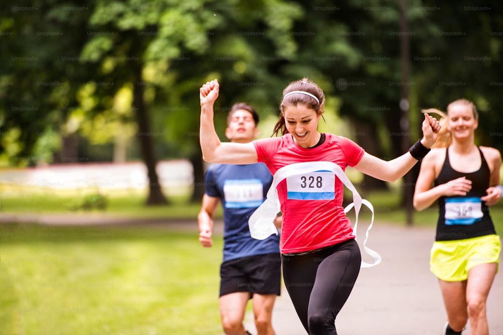 Bella giovane donna che corre tra la folla che taglia il traguardo.