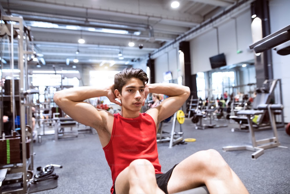 Homme hispanique en forme faisant des craquements, exerçant les muscles abdominaux pendant l’entraînement dans une salle de fitness.