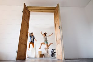 Young married couple moving in a new house, jumping up high.
