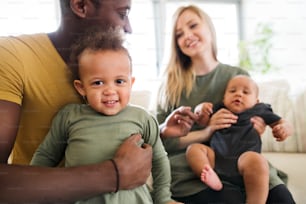 Beautiful young interracial family at home with their cute daughter and little baby son.