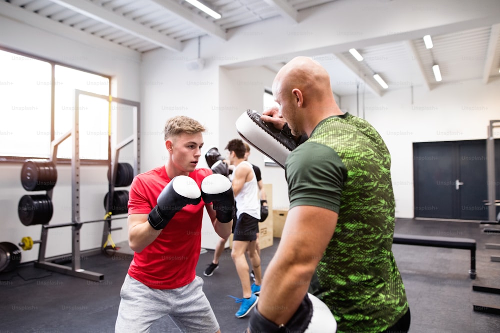 Ein gutaussehender, fitter junger Mann boxt mit seinem Personal Trainer. Athletenboxer mit Boxhandschuhen sparten im Boxstudio.