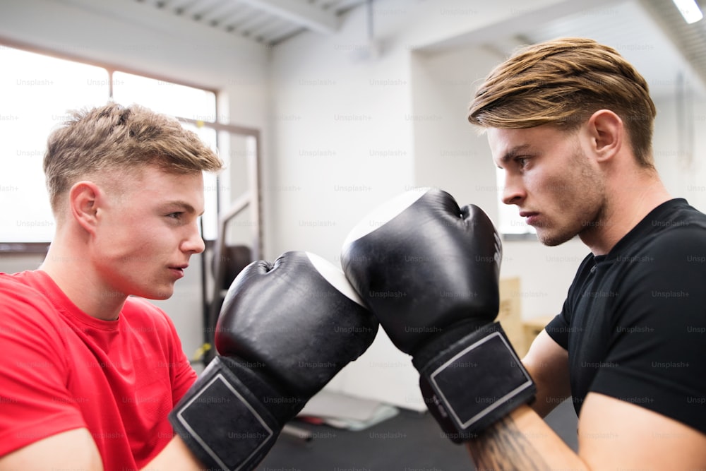 Two fit handsome men boxing. Two athlete boxers wearing boxing gloves sparred in boxing gym.