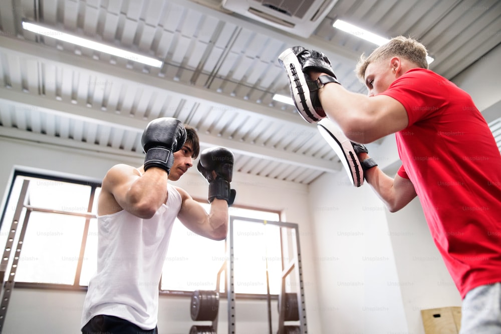 Bel homme hispanique en forme dans la boxe de gym avec son entraîneur personnel