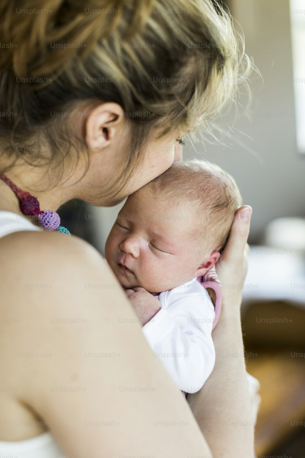 かわいい生まれたばかりの女の赤ちゃんを抱きしめている自宅で美しい若い母親。