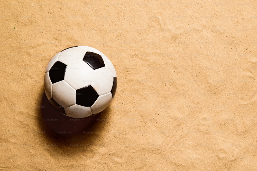 Soccer ball laid on beach. Summer vacation composition. Sand background, studio shot, flat lay. Copy space.