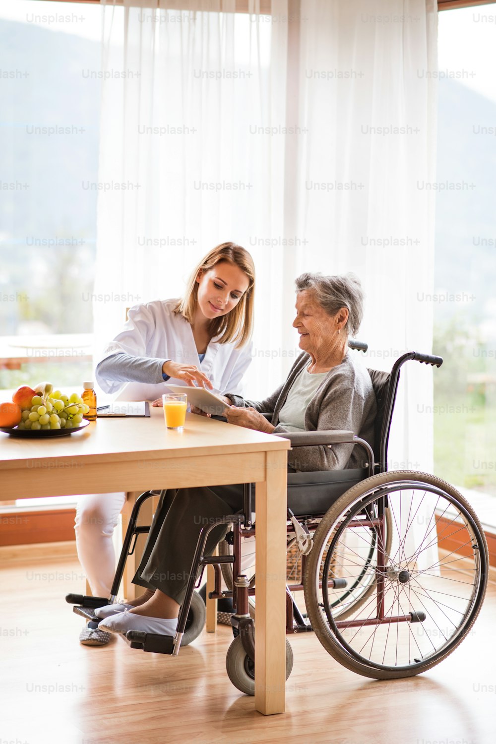 Visitador de salud y una mujer mayor con tableta durante la visita domiciliaria. Una enfermera hablando con una anciana.