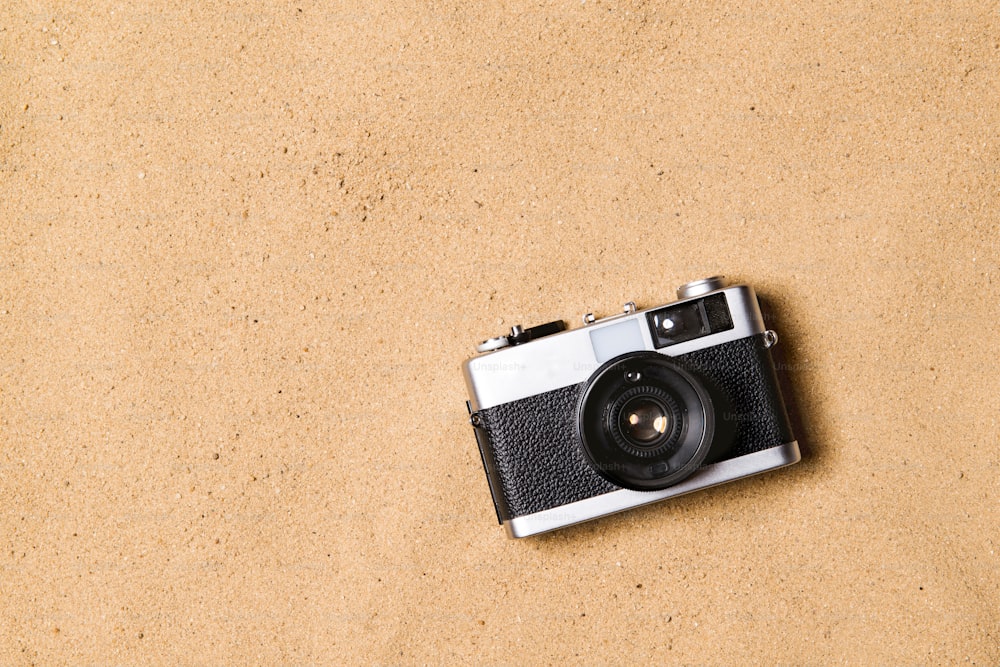 Vintage camera laid on beach. Summer vacation composition. Sand background, studio shot, flat lay. Copy space.