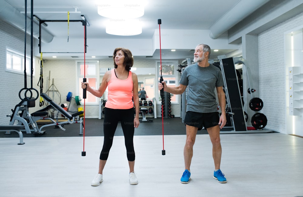 Beautiful fit senior couple in gym working out with vibration bars