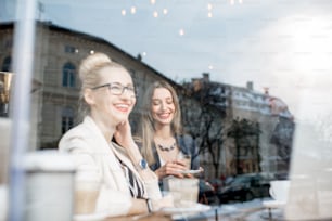 Des gens d’affaires pendant la pause-café près de la fenêtre. Vue à travers la fenêtre avec le reflet de la ville