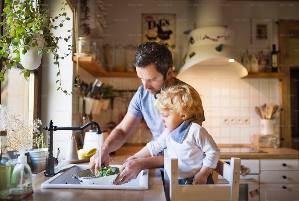 Young father with a toddler boy cooking. A man with his son making vegetable salad.