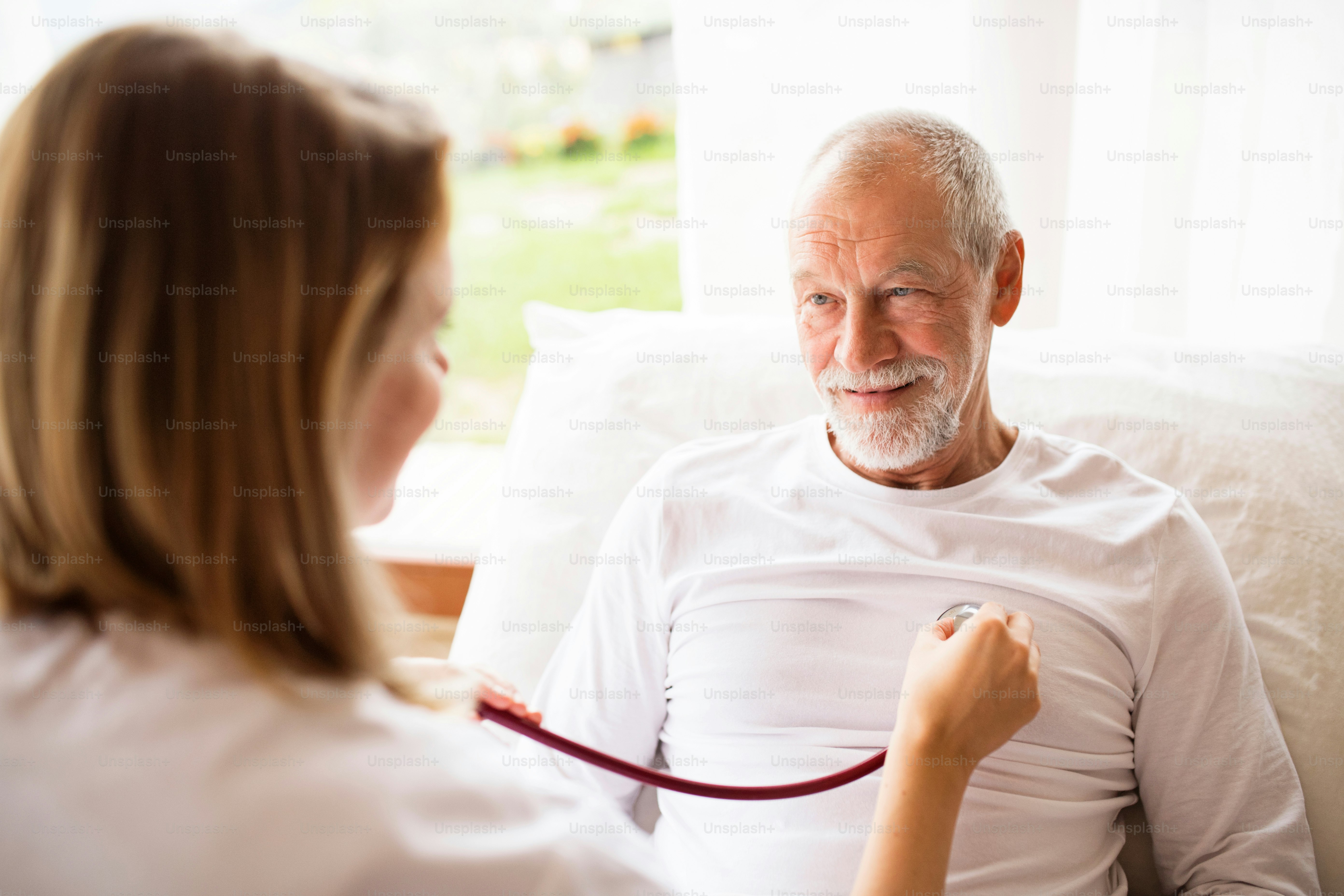 Visiteur de santé et un homme âgé lors d’une visite à domicile. Une infirmière ou un médecin examinant un homme.