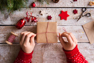Weihnachtlich verpackte Geschenke mit Tannenzweigen und roter Dekoration auf Holztisch