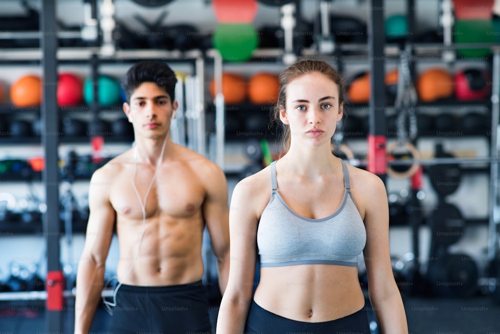 Hermosa pareja joven en forma preparada para hacer ejercicio en el gimnasio moderno.