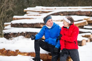 Senior couple jogging outside in winter nature, resting.