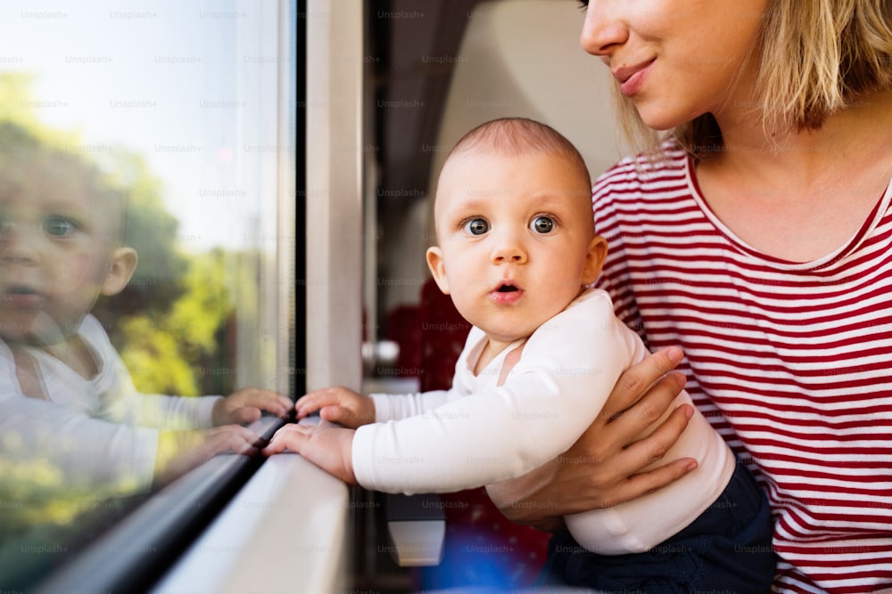 기차로 아기와 함께 여행하는 알아볼 수없는 젊은 어머니. 아름다운 여자와 그녀의 아들의 철도 여행.