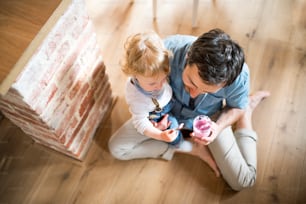 Young father with his son at home eating yoghurt.