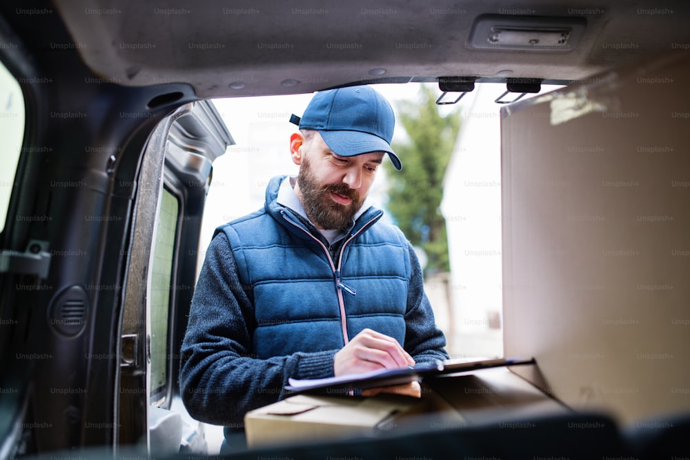 Delivery man delivering parcel box to recipient - courier service concept.