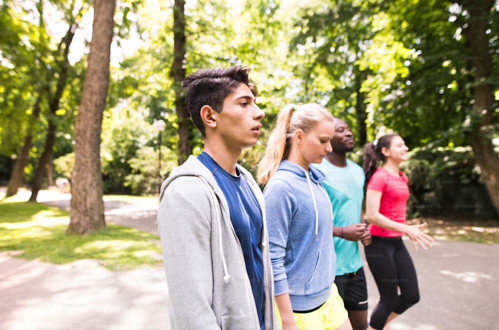 젊은 운동 선수 그룹은 녹색 햇볕이 잘 드는 여름 공원에서 달리기를 준비했습니다.
