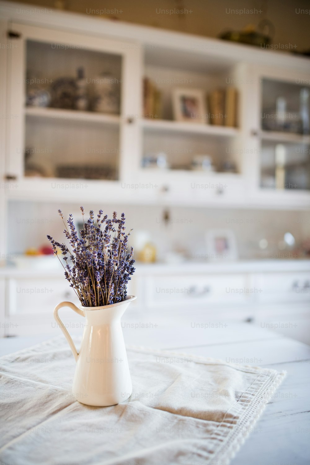 Getrockneter Lavendelstrauß in einer weißen Vase auf dem Tisch in einer Vintage-Küche.