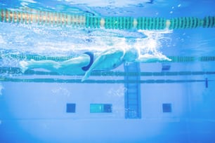 Senior man swimming underwater in an indoor swimming pool. Active pensioner enjoying sport.