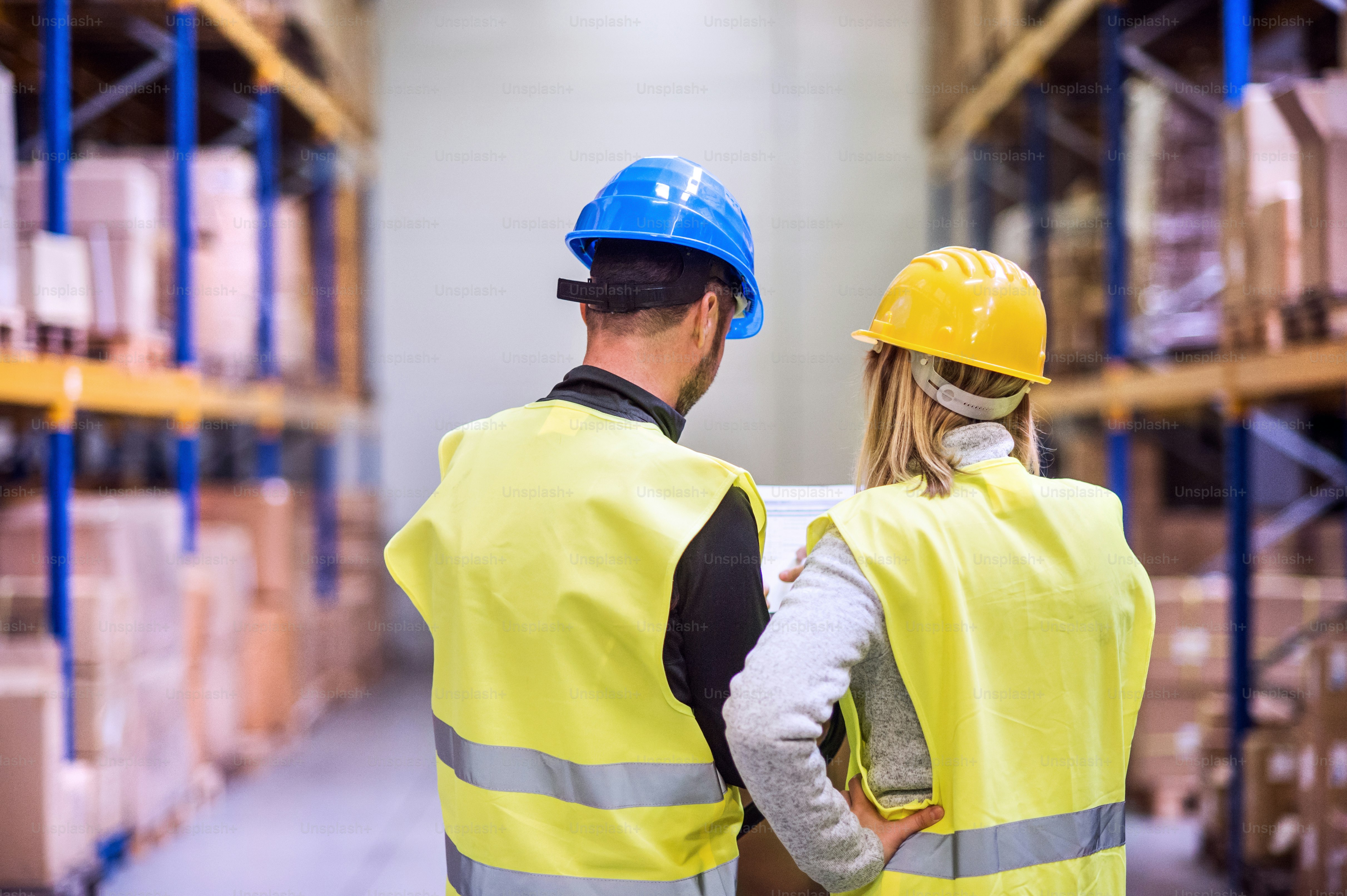 Junge Arbeiter arbeiten gemeinsam in einem Lager. Rückansicht.