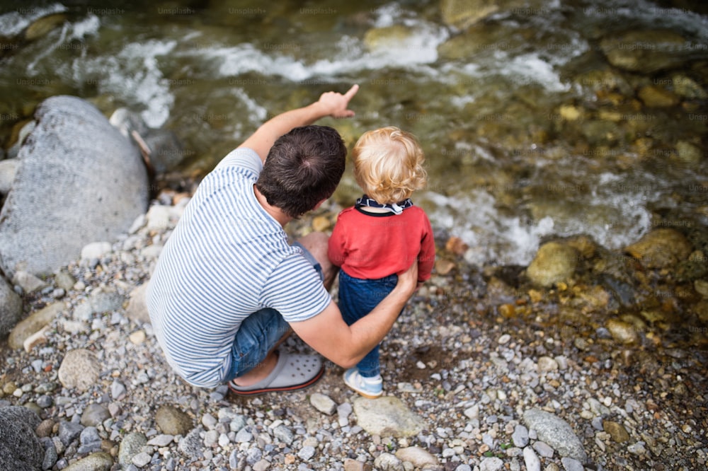 Young father with happy little boy at the river, summer day.