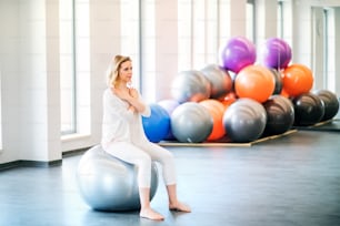 Young beautiful woman doing exercise with a fitball in a gym.