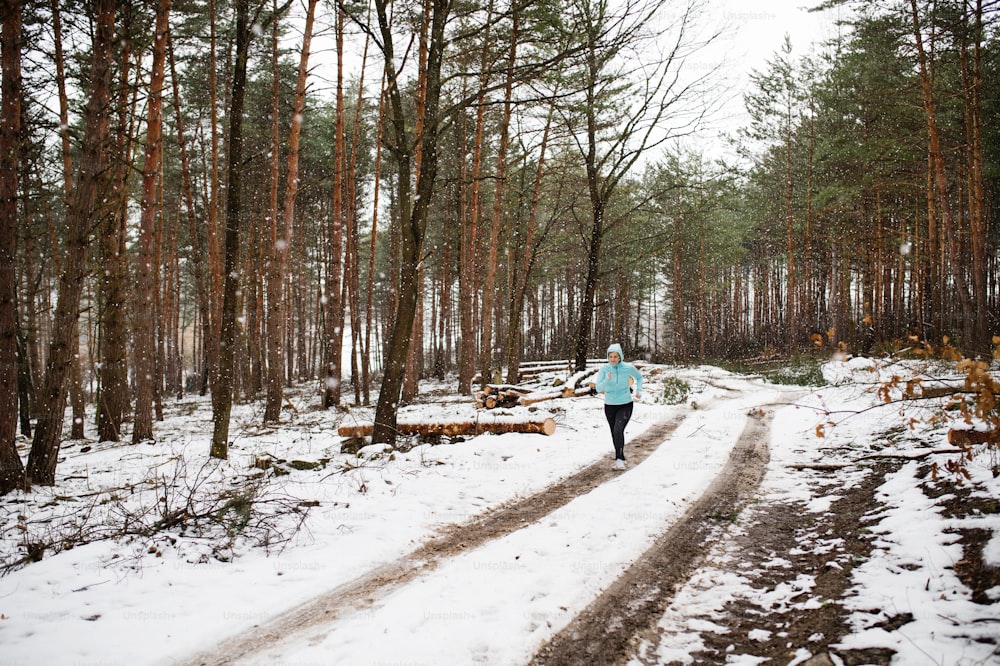Femme âgée faisant du jogging à l’extérieur dans la nature hivernale.