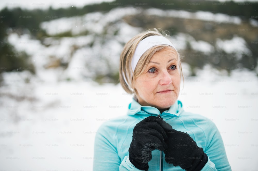 Senior woman jogging outside in winter nature, resting.