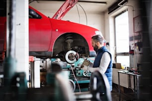Homem maduro mecânico consertando um carro em uma garagem.