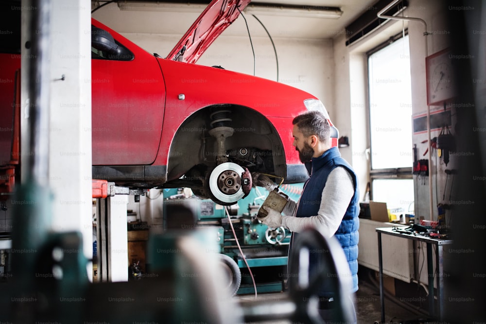 Reifer Mechaniker, der ein Auto in einer Garage repariert.