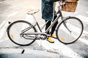 Unrecognizable young woman with bicycle in sunny spring town.