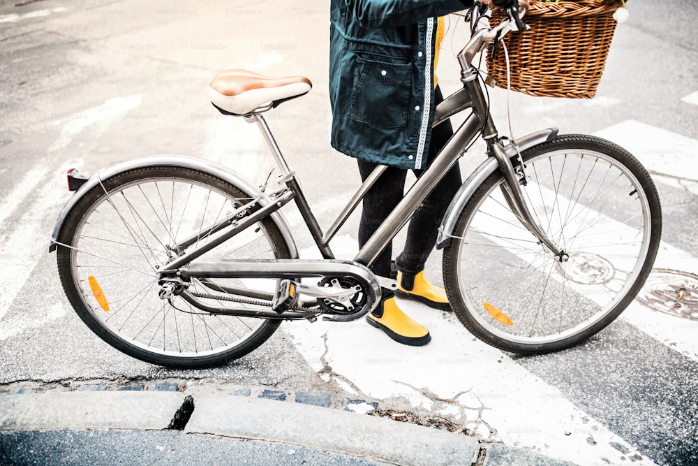 Giovane donna irriconoscibile con bicicletta nella soleggiata città primaverile.