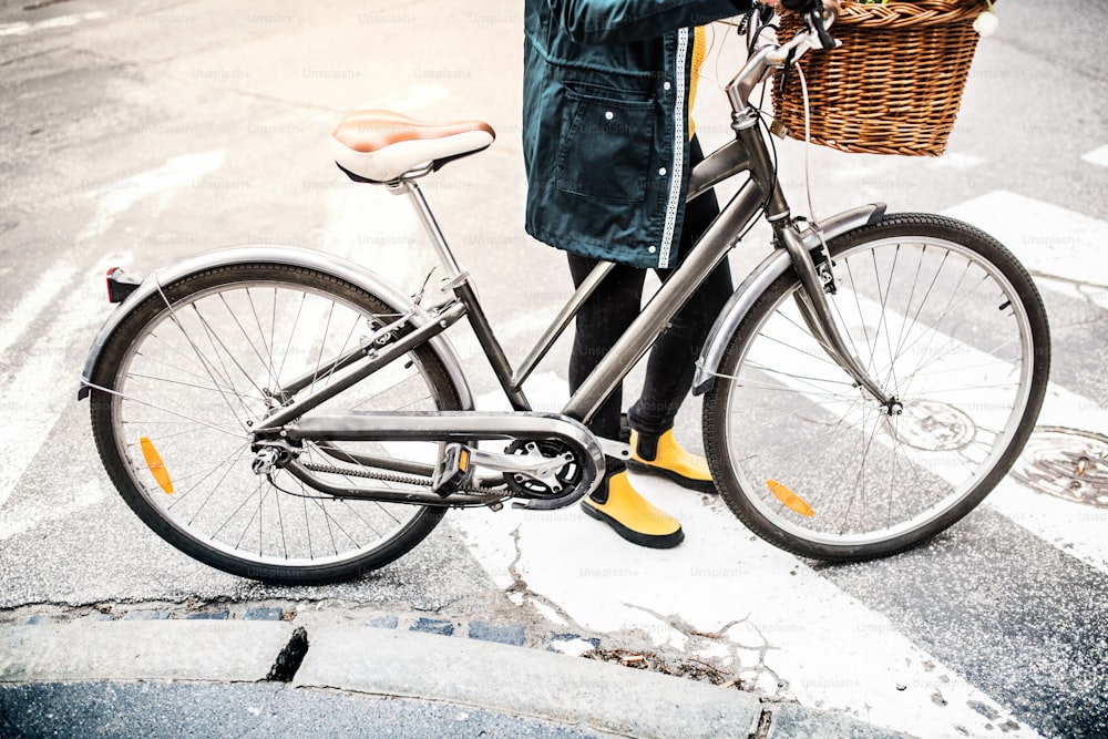 Unrecognizable young woman with bicycle in sunny spring town.