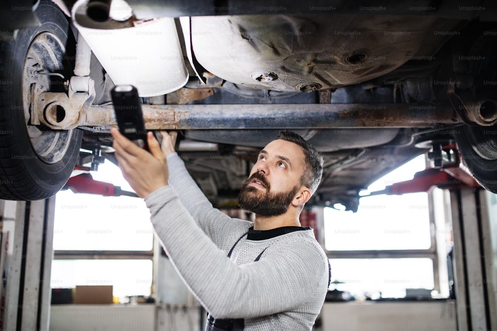 Homem maduro mecânico consertando um carro em uma garagem.