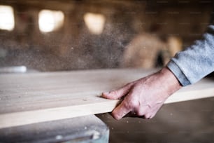 Die Hand eines nicht wiederzuerkennenden Arbeiters in der Schreinerei, der mit Holz arbeitet.