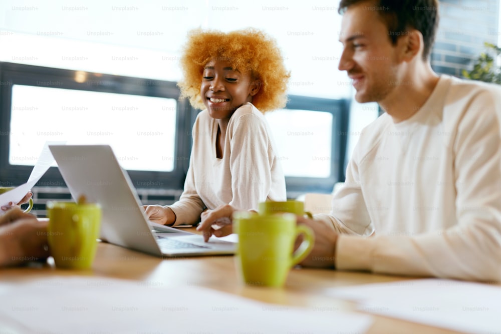 Leute, die an Notebook im Café arbeiten. Lächelnder junger Mann und schöne schwarze Frau, die zusammen an einem Projekt arbeiten, Computer benutzen und Ideen im Café austauschen. Business-Team bei der Arbeit. Hochwertige