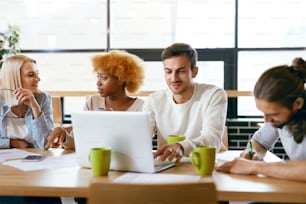 Friends Working Together At Cafe, Using Computer, Drinking Coffee And Sharing Ideas. Beautiful Smiling Women And Handsome Men Talking About Project. Business People Team Work. High Quality