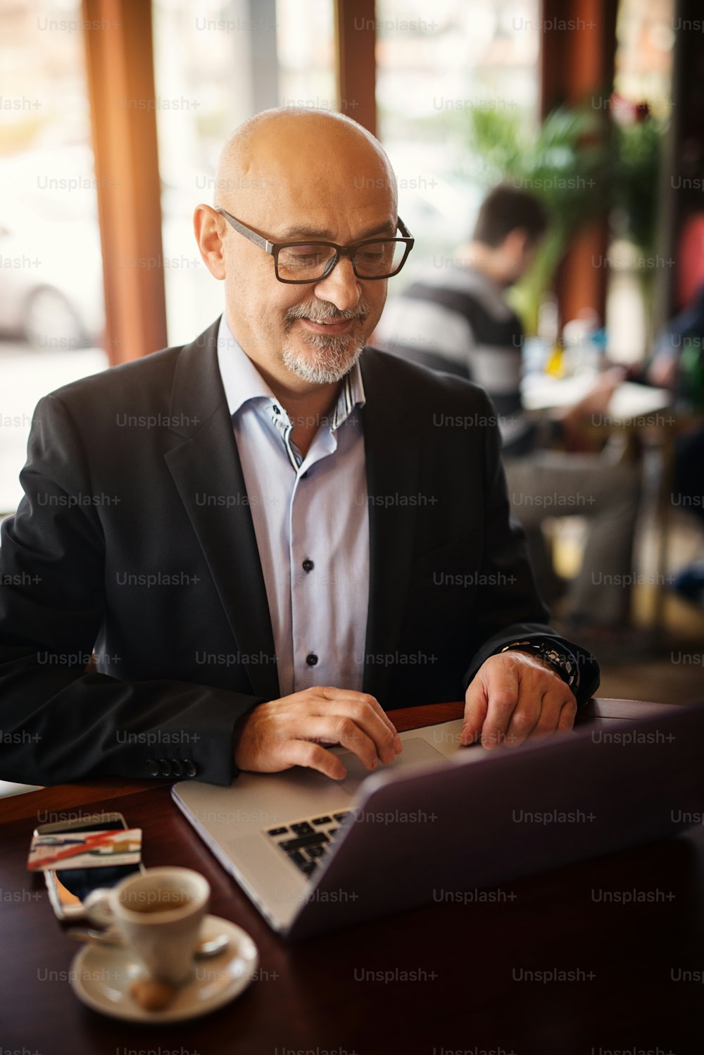 Mature happy businessman is pleased what he sees on his laptop while sitting in a coffee shop.